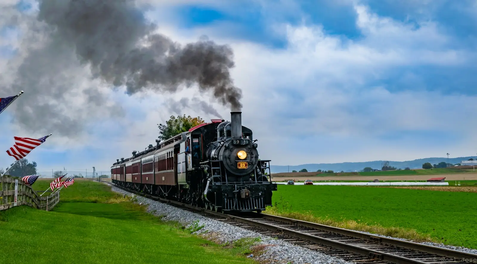 Black-and-red locomotive on rail tracks under blue sky — the chord-horn sound this guide helps you replicate