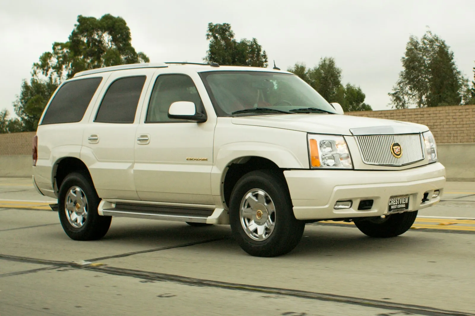 White Cadillac Escalade SUV on a highway — luxury install context for Cadillac