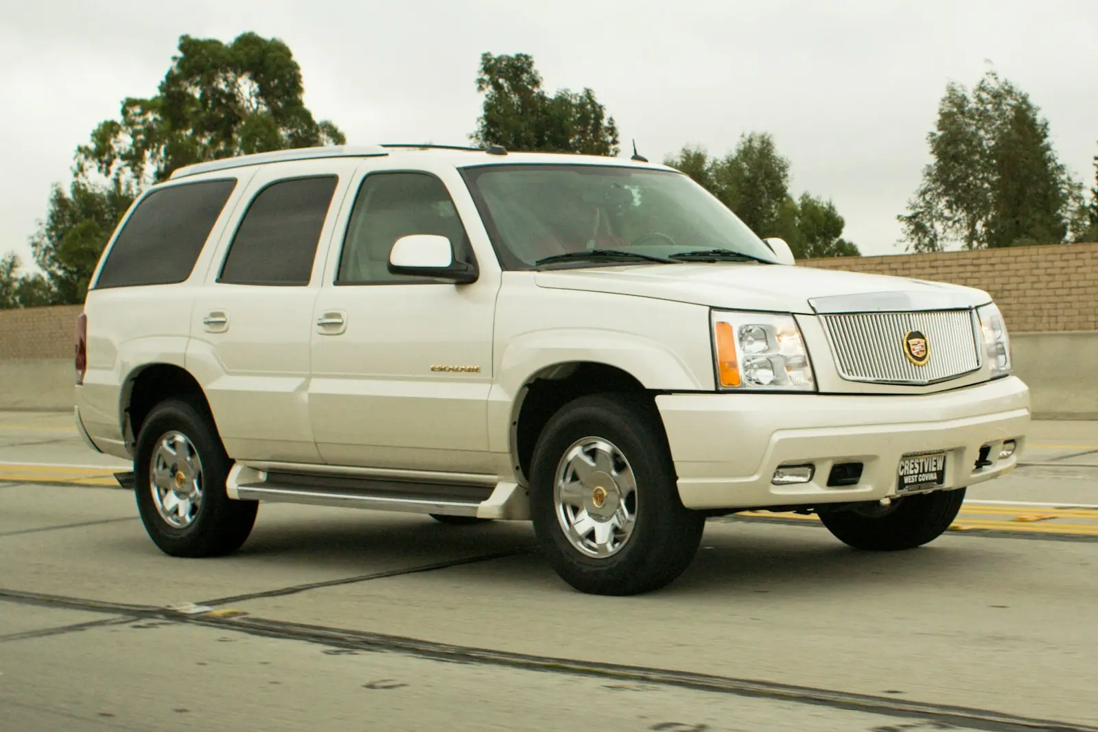 White Cadillac Escalade SUV on a highway — luxury install context for Cadillac
