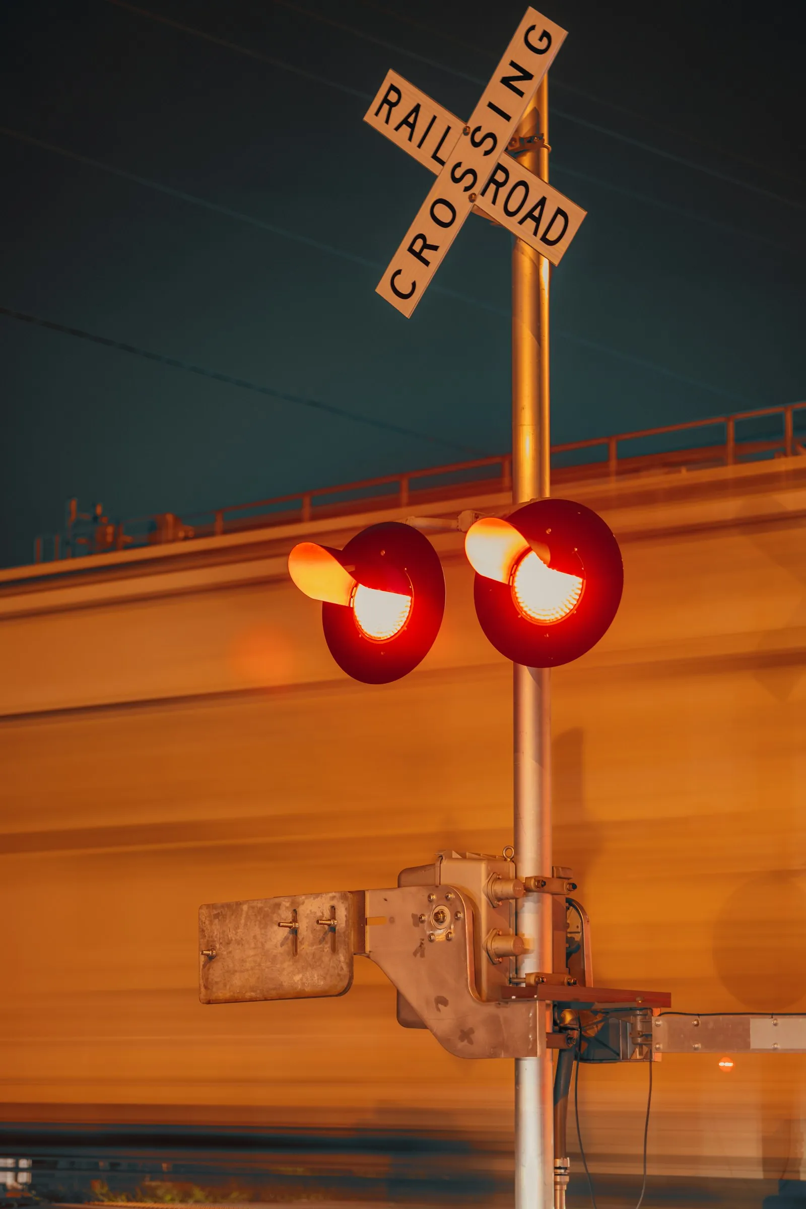 Railroad crossing signal at night with a train passing — the horn rule applies 24/7, with no nighttime exception