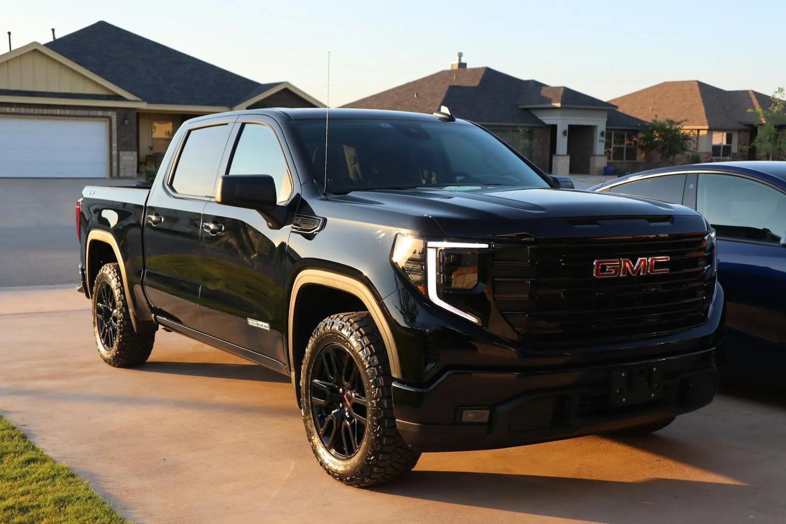 Black GMC Sierra in a driveway — Sierra pickup install context (T1 platform secondary battery tray)