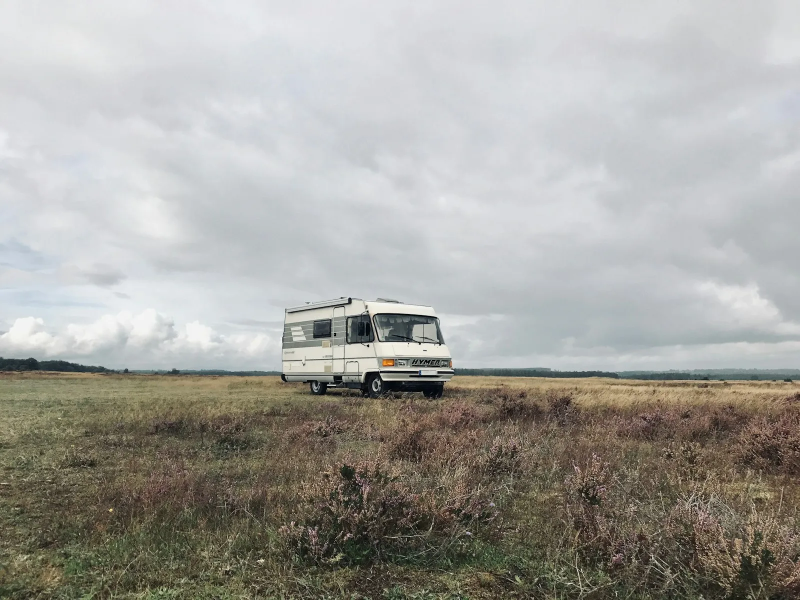 Hymer B564 RV Campervan on a wide field. Grey sky and dry ground