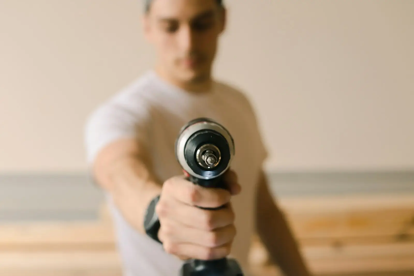 Man in white crew neck t-shirt holding black and silver dumbbell