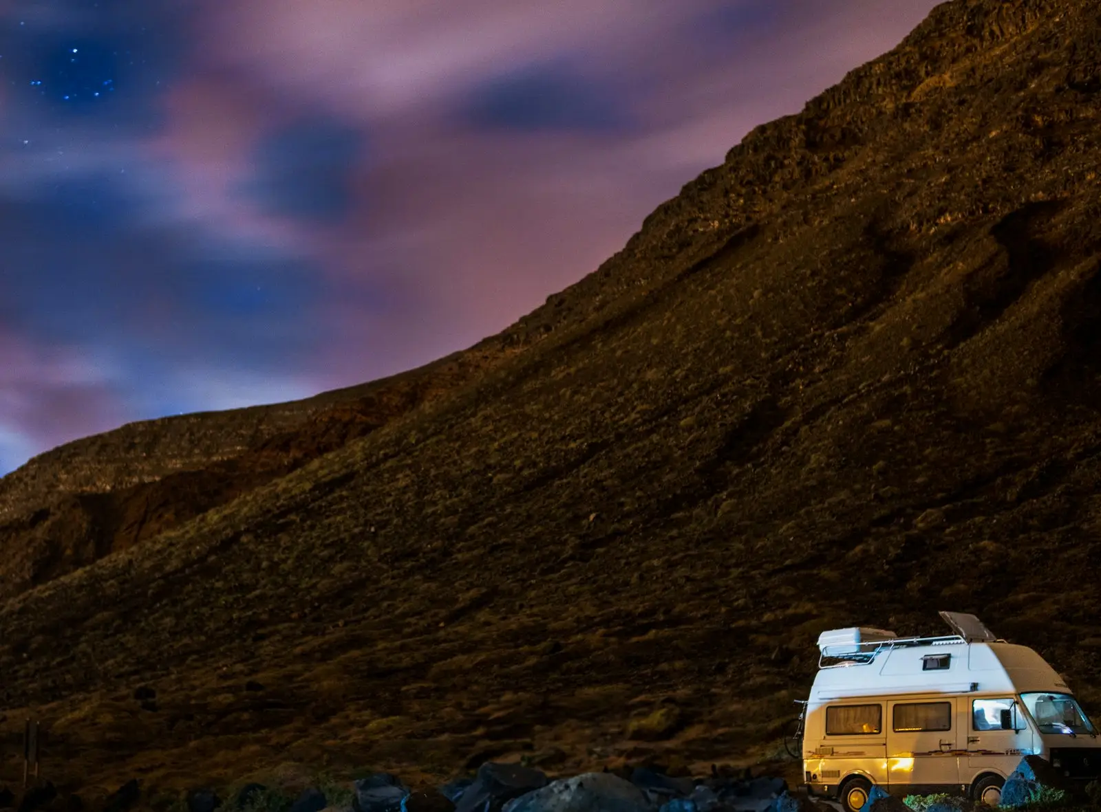 Camper van parked at the base of a rocky mountain