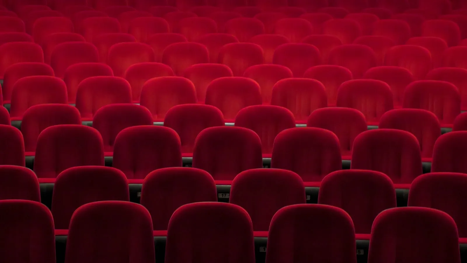 Red padded theater chairs — cinema setting where train horns appear in soundtrack and on-screen