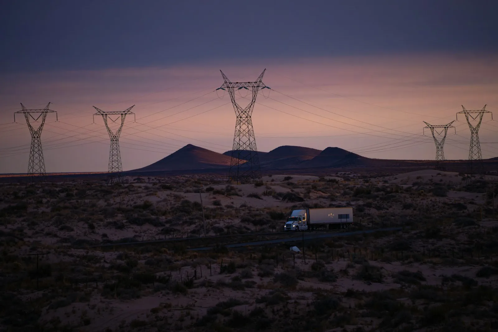 Power lines and truck in desolate landscape at dusk