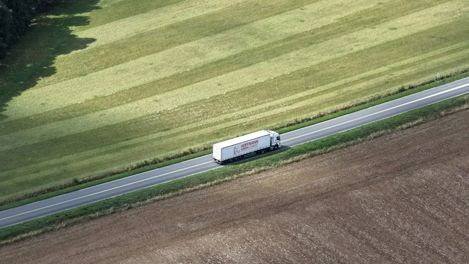 White truck driving on a road through fields