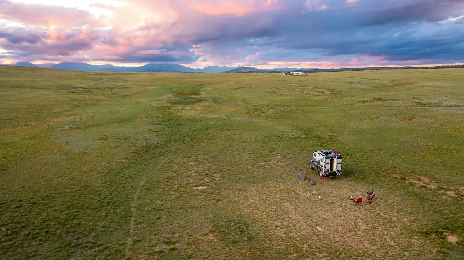 RV truck camper setup for camping in a field at sunset in Colorado.