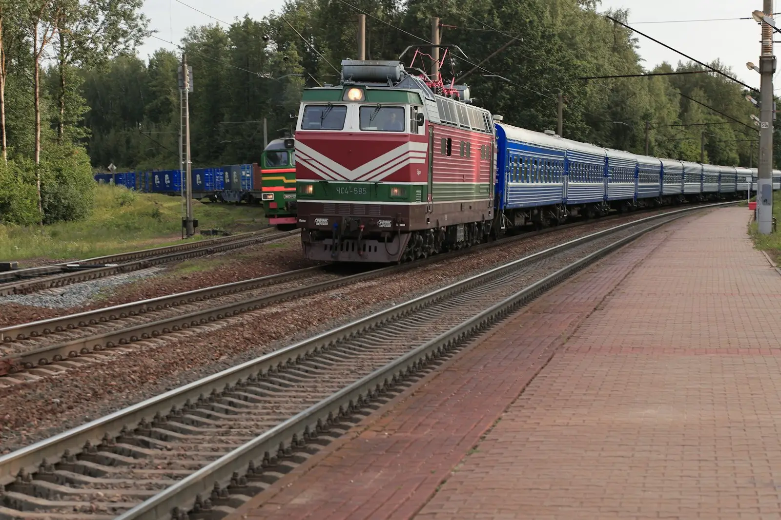 A passenger train overtakes a freight train on an adjacent track