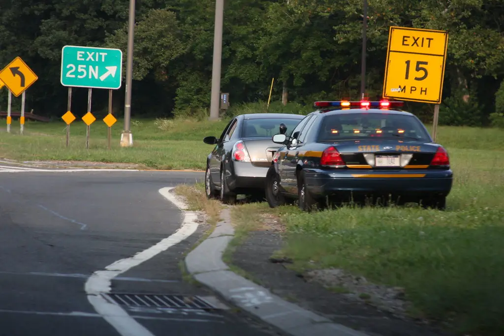 Police cruiser with lights on behind a stopped vehicle during a roadside traffic stop