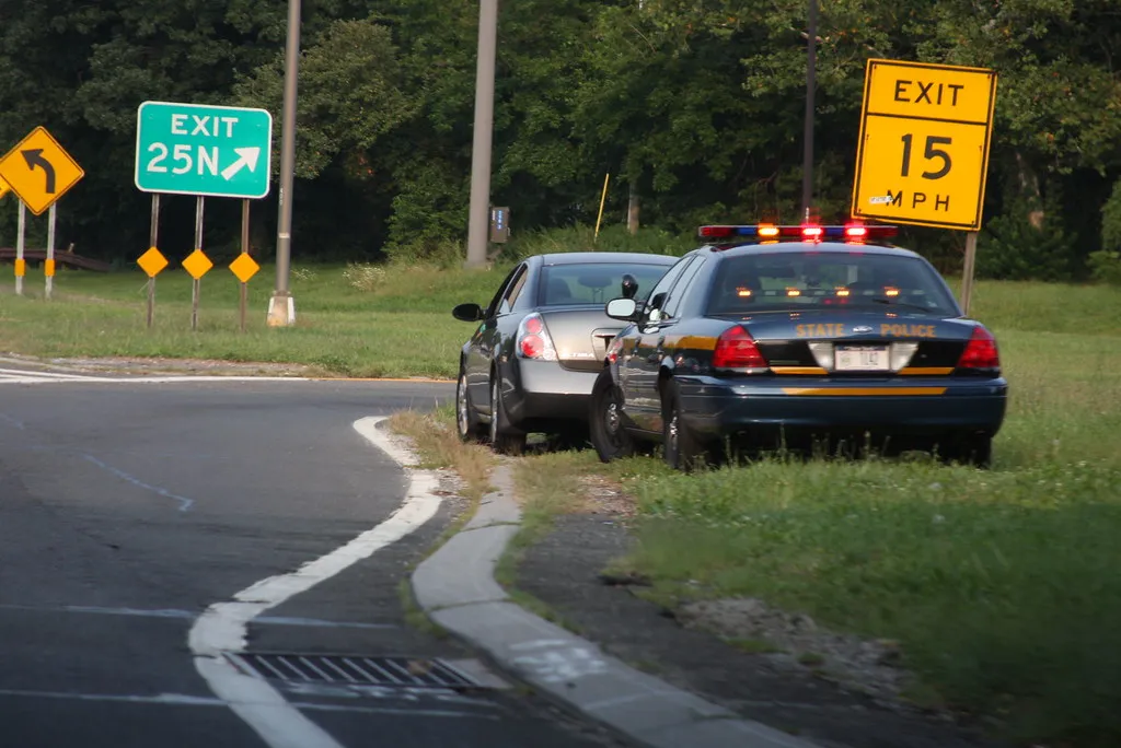 Police cruiser with lights on behind a stopped vehicle during a roadside traffic stop