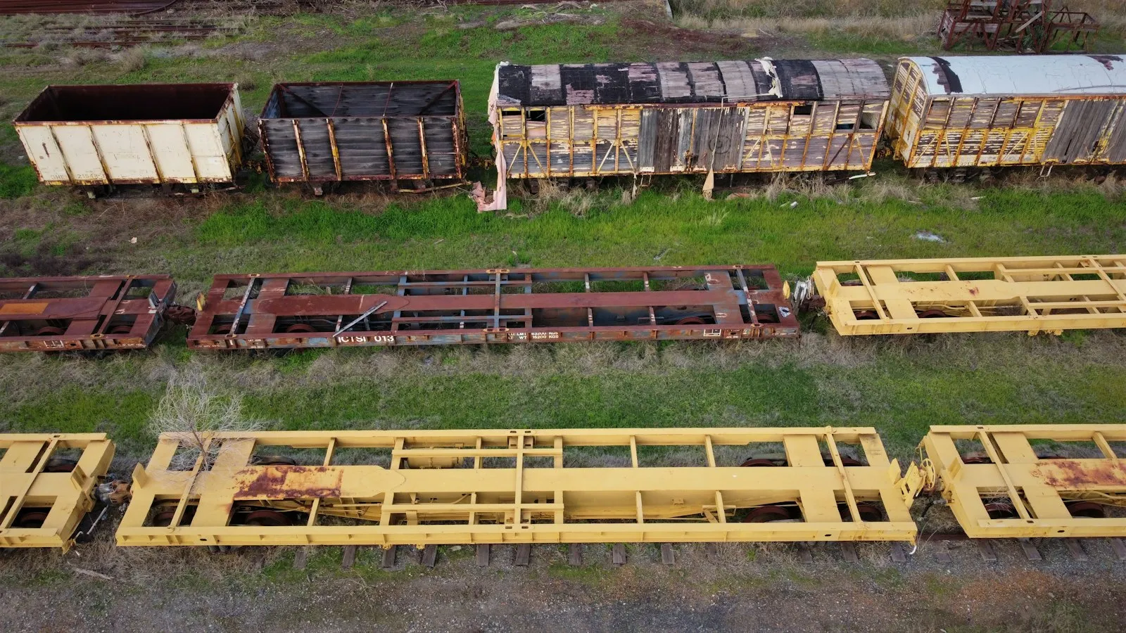 A group of train cars sitting on top of a grass covered field