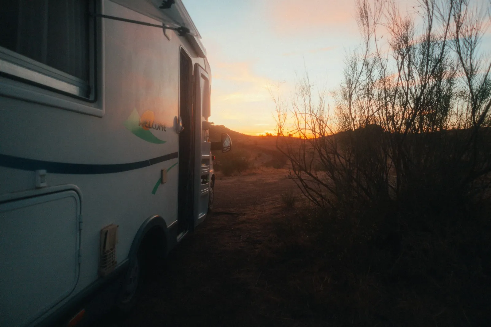 An rv parked in the desert at sunset